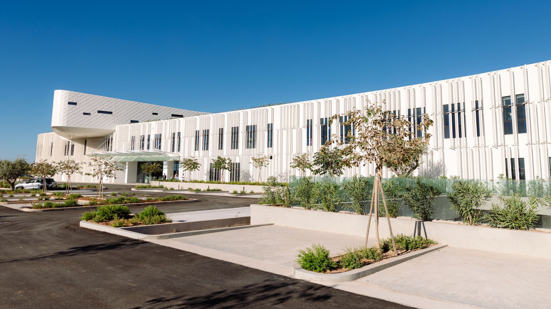 The white, modern facade of Athens LifeTech Park in Greece under a clear blue sky