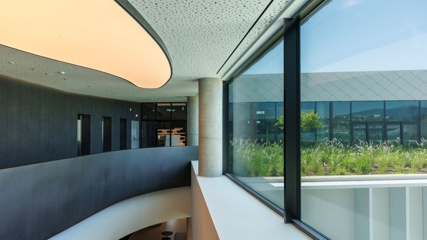 Interior of Athens LifeTech Park, with a curved atrium and floor-to-ceiling windows onto a planted courtyard